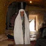 The ancient Berber lady who lives in a cave, showing off with a pale full of water on her head. 